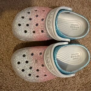 Kids’ glitter Crocs in a fun ombré design, featuring pink, silver, and blue hues